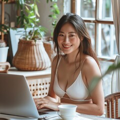 A Japanese woman, adorned in a white swimsuit, beams while engrossed in her laptop work at her workstation, displaying commitment and effectiveness in her job duties.
