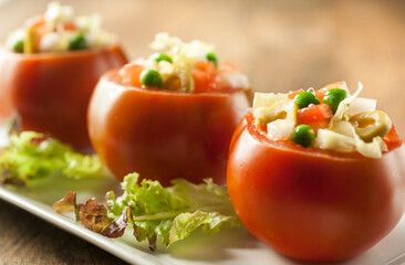 Front view of three tomatoes stuffed with vegetables and green olives