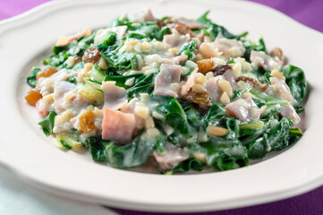 Plate of boiled acellgas with ham, raisins and pine nuts in skim milk sauce