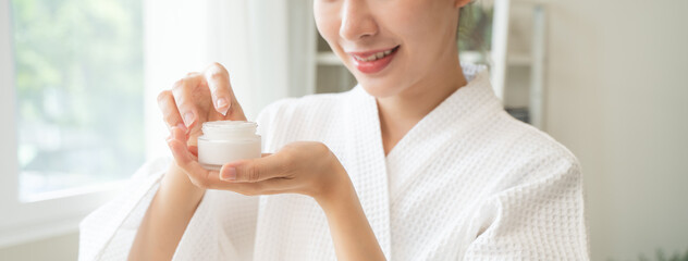 Close-up woman using skin care serum cream in daily routine.