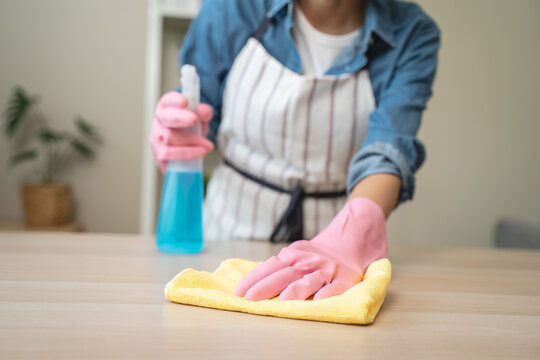 Close-up hand of maid cleaning table during household job.