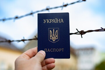 Ukrainian passport against the background of barbed wire. Violation of the law for the departure of...