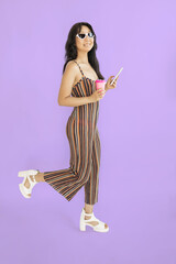 Full length image of young Asian woman using smartphone on violet background.