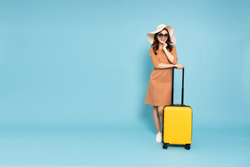 Happy young Asian woman traveler with luggage isolated on sky blue background, Tourist girl having...