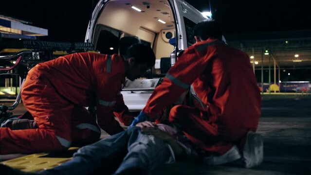 Asian man emergency medical technician (EMT) or paramedic nurse transporting a patient to the hospital by ambulance car