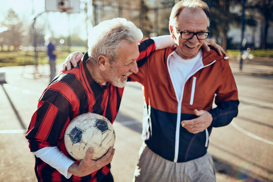 Fototapeta Two active senior men hugging after soccer game in the park