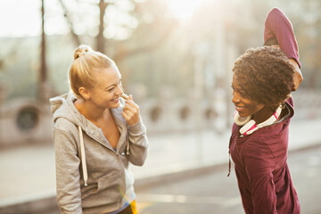 Two women stretching after running in urban environment