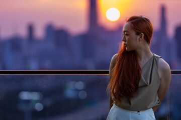 Brunette woman is crying at the balcony during sunset with cityscape view for ptsd and depression...