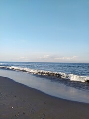 ocean wave on the island of Bali crashes onto the rocky shore, a clear sunny day, blue sky