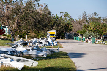 Heaps of debris rubbish on street side near severely damaged by hurricane houses in Florida mobile...