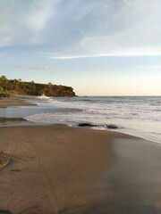 The sandy beach of the ocean with an incoming wave, a fresh morning, the landscape of Bali