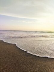 The sandy beach of the ocean with an incoming wave, a fresh morning, the landscape of Bali
