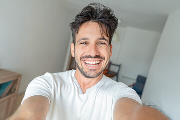 Handsome young man taking selfie with smart mobile phone indoors - Happy guy smiling at camera - People and technology life style concept