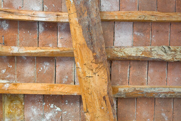 Old traditional italian wooden ceiling with damaged wooden beams, rafters and terracotta tiles clay...
