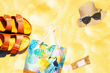 Summer vacation background. Brown sandals, beach bag, creme, hat and sunglasses on a golden sunny...