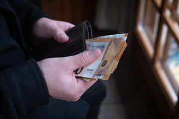 gros plan sur des mains qui tiennent une liasse de billets de 50 euros pour effectuer un paiement