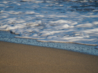 Photo on the surface of crashed waves on the beach of the coast. Tropical surf on the beach. waves on the golden sand of the beach. Fantastic sea view with calm sea water waves and sunlight