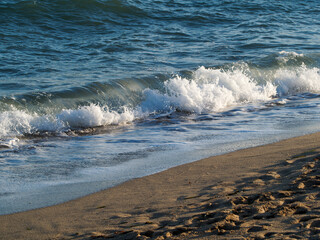 Photo on the surface of crashed waves on the beach of the coast. Tropical surf on the beach. waves on the golden sand of the beach. Fantastic sea view with calm sea water waves and sunlight