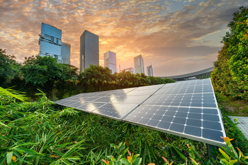 Ecological energy renewable solar panel plant with urban landscape landmarks in sunset