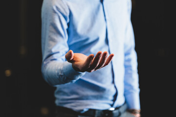 giovane uomo adulto, irriconoscibile e vestito elegante che porge la mano su sfondo scuro. concetto...