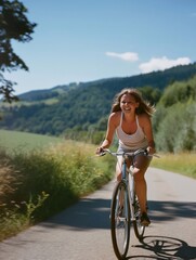 smiling beautiful woman riding a bike in a wild road in the countryside leading to rolling hills and forested areas on both sides under a clear blue sky. generative AI