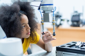 Kid female teen child enjoy Machine Learning Robot arm is Moving Under Control robot at technology...