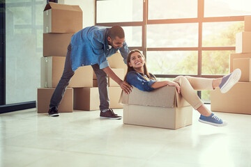 New home, playful and couple with box for moving for house, property mortgage and real estate...