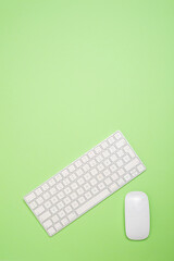 computer keyboard with a mouse on a green background. Copy space