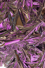 a close up of a pile of crumpled aluminum foil with purple lights behind it