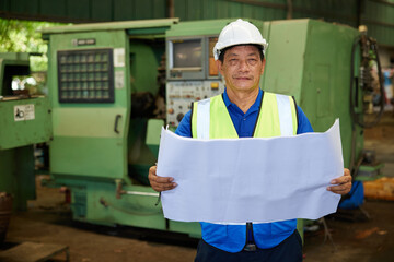 senior worker holding and reading blueprint paper in the factory