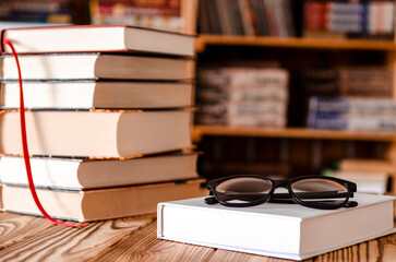 ok stacked with Eyeglasses on wooden Table with blurred Bookshelf in library