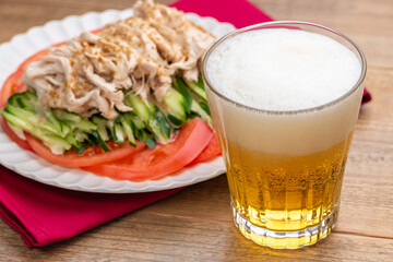 グラスにいれたビールと棒棒鶏（バンバンジー）