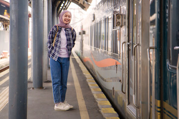 full lenght shoot of happy asian muslim woman smiling happy while standing on train station...