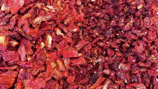 Red sun-dried tomatoes fill the frame seen from above in slider shot