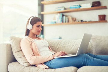 Woman, laptop and headphones with video on sofa in home for audio streaming, subscription service...