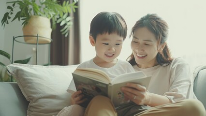Small asian kid reading a book happily together with his mother