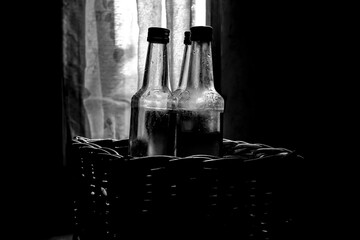 Several bottles are in a rattan basket isolated on a dark background