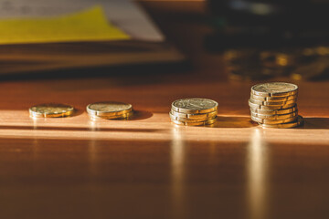 vista macro, leggermente dall'alto, di varie pile di monete su una scrivania, viste di lato, dalla...