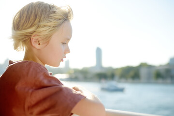 Cute blonde preteen boy is traveling by boat or ferry on the sea. Family vacations on ocean or sea. Summer leisure for families with kids.