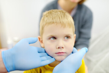 A cute toddler boy with his mother are at an appointment with a pediatrician. The doctor ENT is...