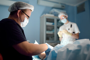 Professional vascular surgeon and assistant in the operating room of the clinic during vein surgery. Phlebectomy. DVT