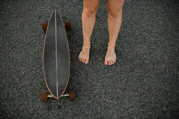 Minimalist stroll. Girl's legs, longboard, road beneath them.