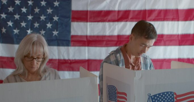 A diverse group of voters entering and exiting voting booths at a polling  station with American Flag in the background