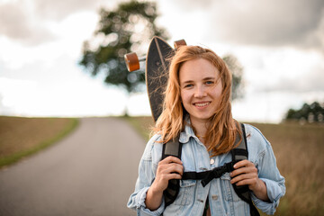Happy moment. Girl with a longboard, standing and smiling.