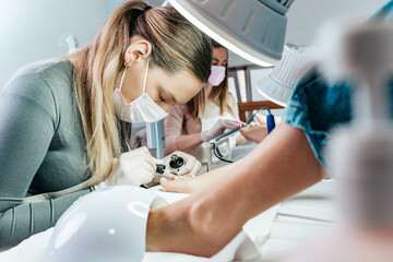 Group of professional podiatrists working in a modern nail beauty studio or spa. Satisfied clients relaxing and enjoying in a great foot and toenails treatment.