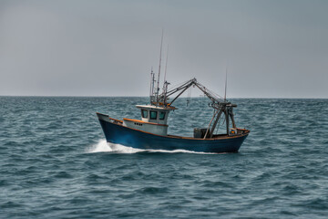 Fototapeta premium Old fishing boat sailing along the bay
