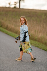 Fototapeta premium Girl with longboard, smiling, faces the country road's open expanse