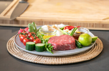 The uncooked ingredients prepared for making yum steak, spicy Thai salad style, are arranged and placed on a local tray set.