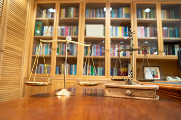 Comparison between Gold Vintage and Modern scale lay on wood table in front of library book shelf.