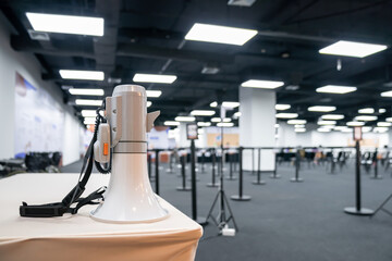 Two white - gray MEGAPHONE are laid on cream table in empty hall, ready to used for event corona...